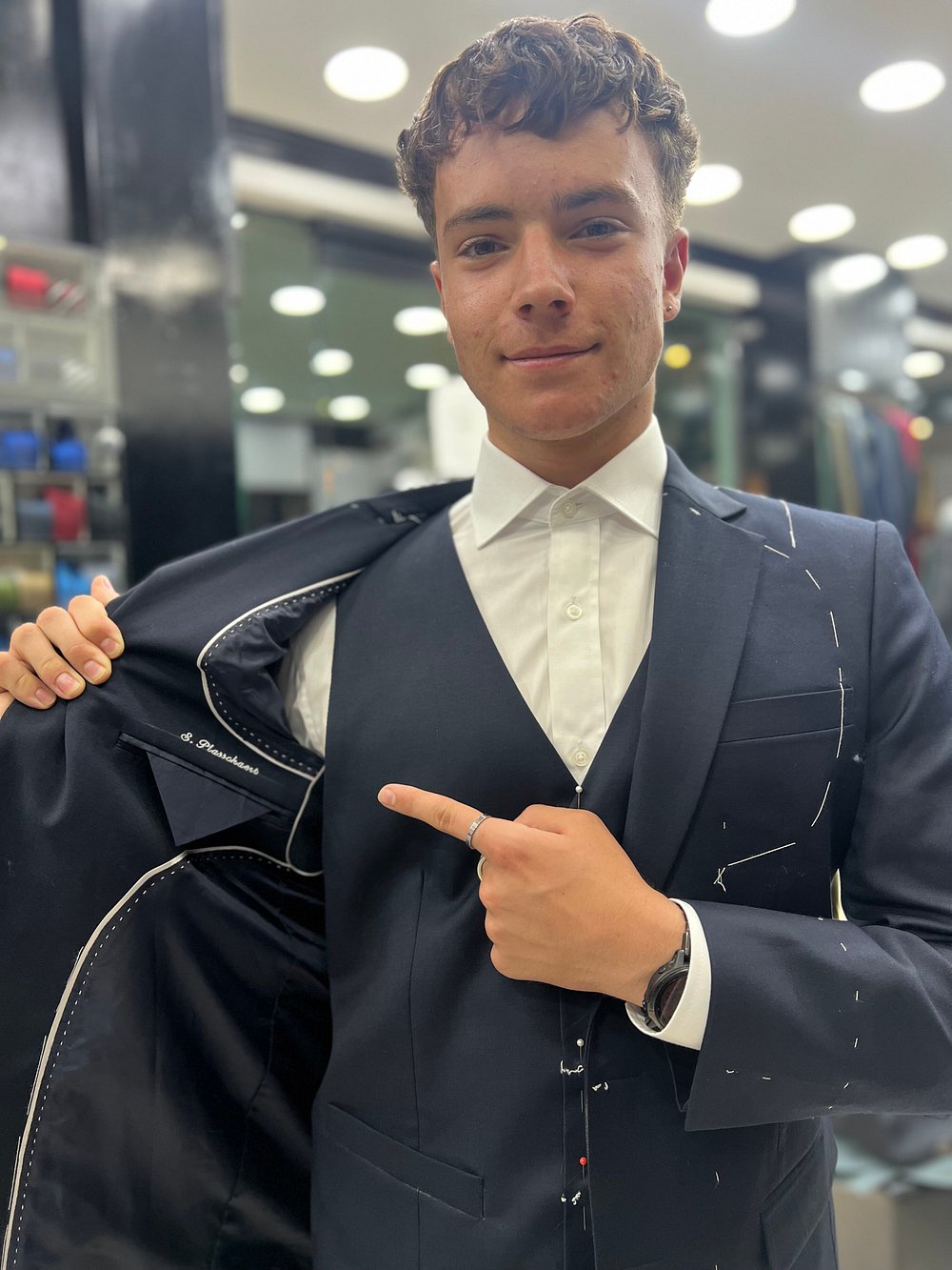 A hand-tailored navy three-piece suit being fitted, basting stitches still in place